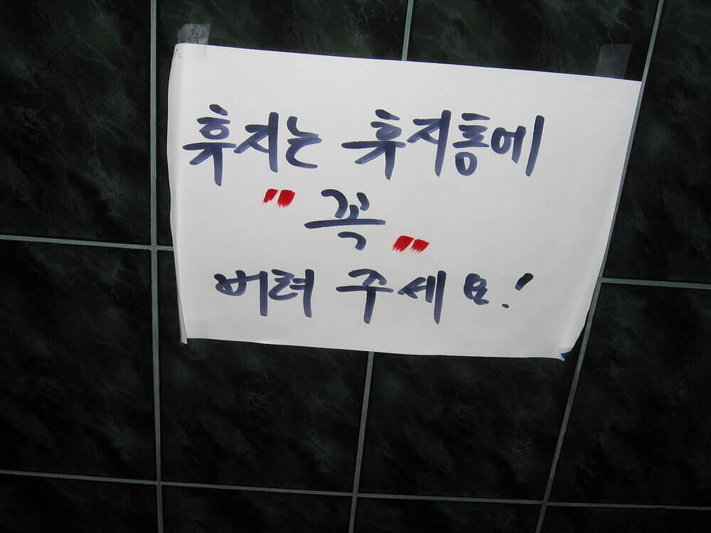 Sign taped accross from toilet