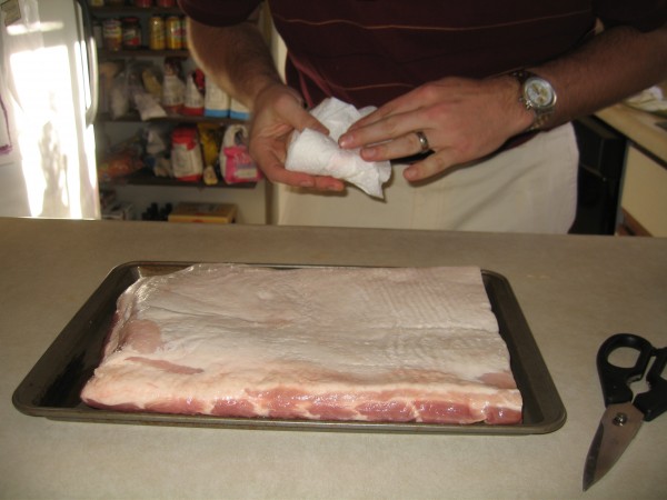 Wiping off the pork belly with papertowels.